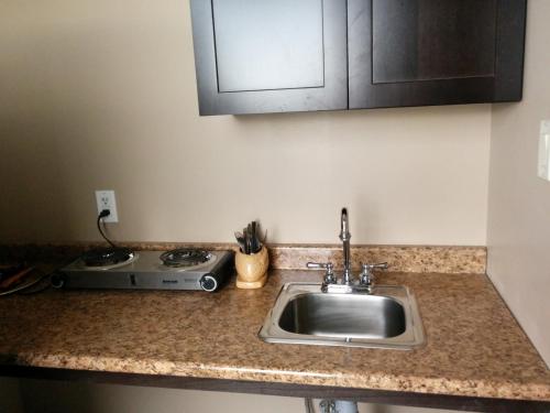 a kitchen counter with a sink and a stove at Bonnyville Hotel in Bonnyville