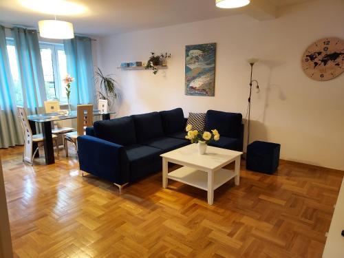 een woonkamer met een blauwe bank en een tafel bij APART- salon z aneksem kuchenym, 2 sypialnie, łazienka in Szczecin