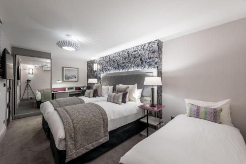 a hotel room with two beds and a desk at Mercure London Hyde Park Hotel in London