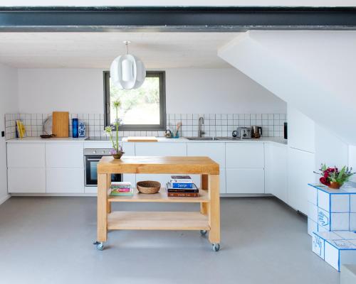 eine Küche mit weißen Schränken und einem Holztisch in der Unterkunft l'Atelier des Milles Roches in Gordes