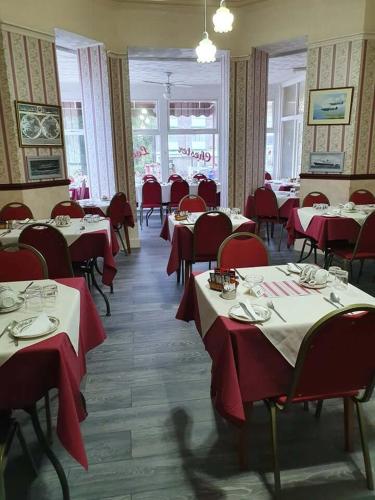 a dining room with tables and chairs and red clothed tables at Chester Lodge in Sandown