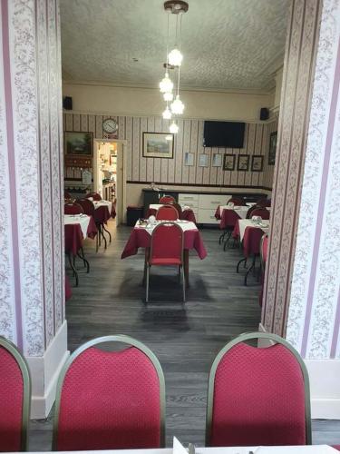 a dining room with tables and red chairs at Chester Lodge in Sandown