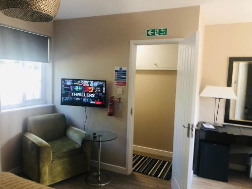 a room with a chair and a television on the wall at The Annexe II in Mildenhall