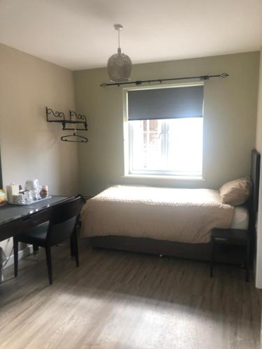 a bedroom with a bed and a desk and a window at The Annexe II in Mildenhall