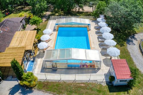 une vue aérienne sur une piscine avec des parasols et une piscine dans l'établissement VILLAGE DE GITES LA TRUFFIERE, à Orliaguet