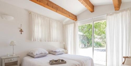 a white bedroom with a bed and a large window at romantique villa provencale in Bargemon