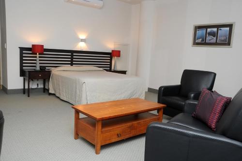 a hotel room with a bed and a table and chairs at Emerald Hotel in Gisborne