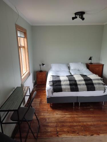 a bedroom with a bed and a table and a window at Happy-Cove Guesthouse - by the sea in Bakkafjörður