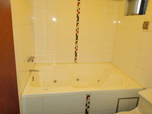 a bath tub in a bathroom with white tiles at Gran Hotel Ica in Ica