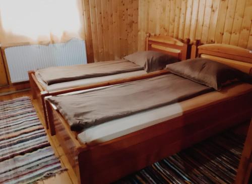 two twin beds in a room with wooden walls at Cabana Roșia in Roşia