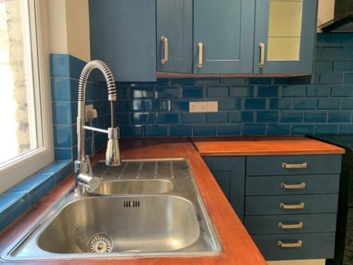 a kitchen with a stainless steel sink and blue cabinets at LFC Staycation in Liverpool