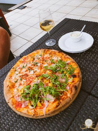 a pizza sitting on a table with a glass of wine at Romeo&Julia in Toruń