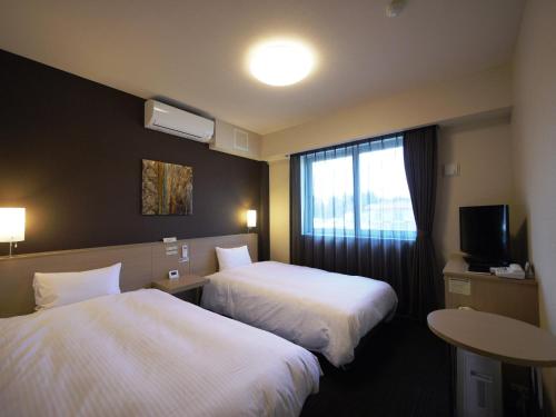 a hotel room with two beds and a window at Hotel Route-Inn Tome in Tome