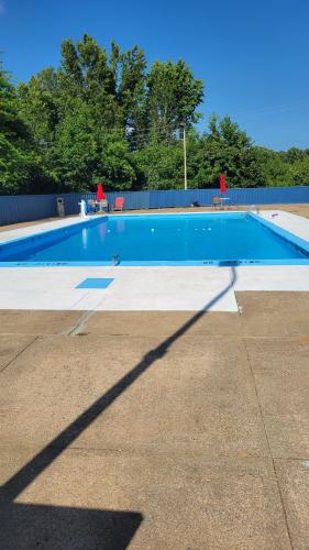 a large blue swimming pool with a long shadow at AmeriVu Inn-Gilbertsville in Gilbertsville