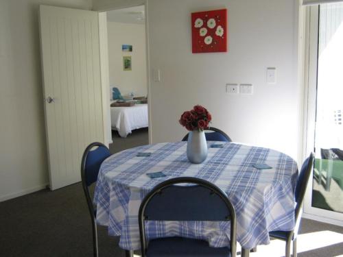 Una mesa azul y blanca con un jarrón de flores. en Cathedral Cove Apartment, en Hahei