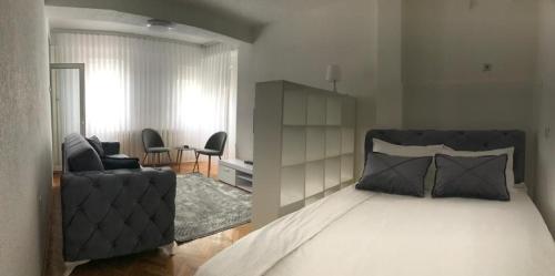 a bedroom with a bed and a living room with a couch at Stan Na Dan in Novi Pazar