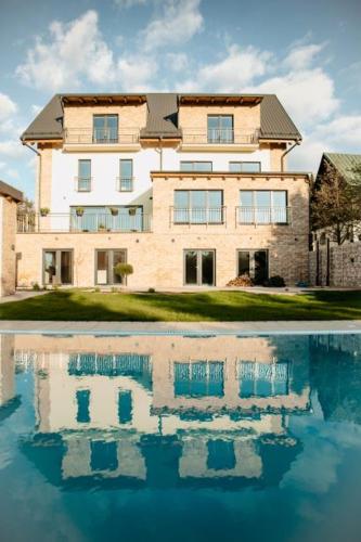 a large building with a reflection in a pool of water at Joy Aparthotel Keilberg in Klínovec