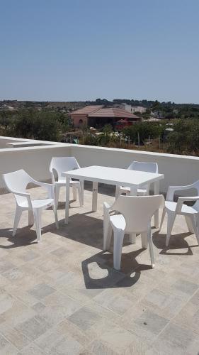 een groep witte tafels en banken op een dak bij Casa Aranci@verde in Marsala