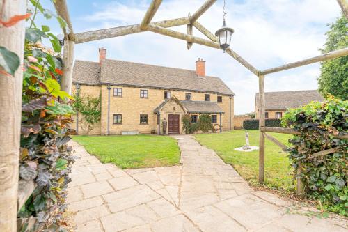 an external view of a large house with an archway at Fawlty Fields in Aynho