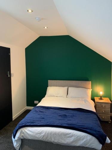a bedroom with a green wall and a bed at LFC Staycation in Liverpool