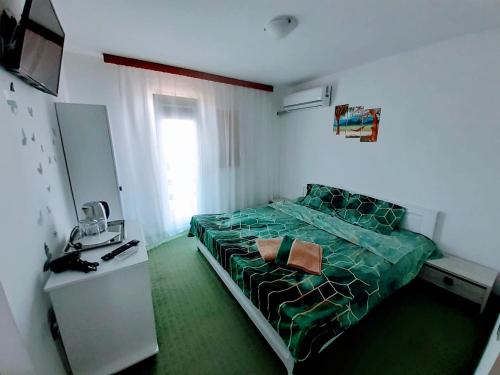 a bedroom with a bed with a green comforter at Vila Atipic in Costinesti