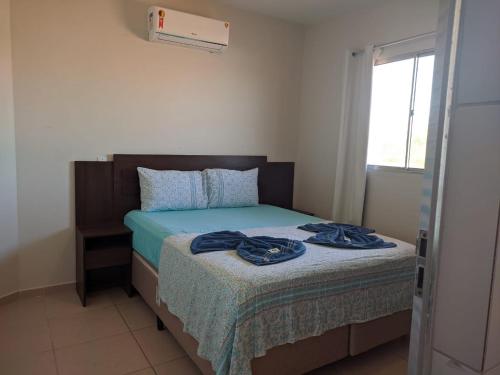 a bedroom with a bed with blue sheets and a window at Pousada O Mineiro - frente para o rio in Galinhos