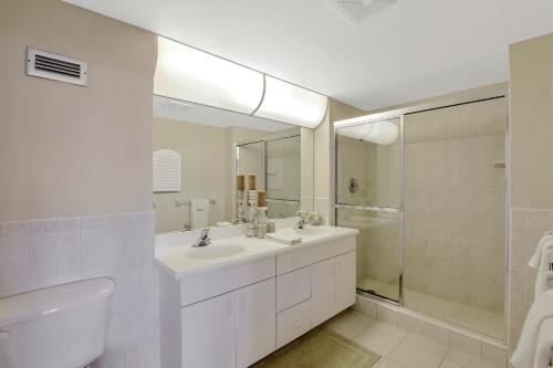 a white bathroom with a sink and a shower at Sunny beachfront condo with pool and SW-facing balcony in Marco Island