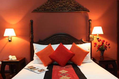 a bedroom with a bed with orange walls and red pillows at Chandara Boutique Hotel in Vientiane