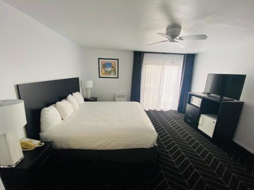 a hotel room with a bed and a ceiling fan at Masterpiece Hotel in Morro Bay