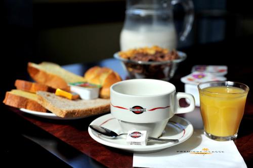 une tasse de jus d'orange et une assiette de pain et de pain grillé dans l'établissement Hôtel & Résidence Avermes, à Avermes
