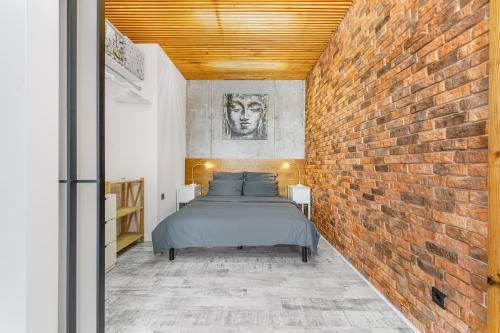 een slaapkamer met een bakstenen muur en een bed bij Tender loft in Odessa