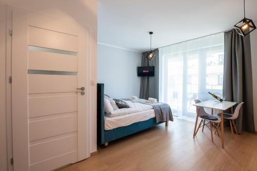 a bedroom with a bed and a desk and a table at Drwinka Park Apartment in Krakow