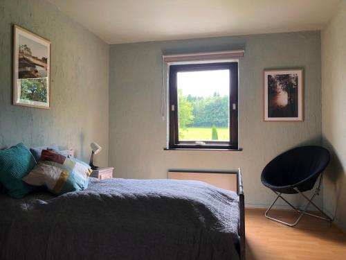 a bedroom with a bed and a window and a chair at Les Caliciades 3 à Gros-Fays in Bièvre