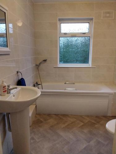 a bathroom with a tub and a sink and a window at The Ramblings in Wexford