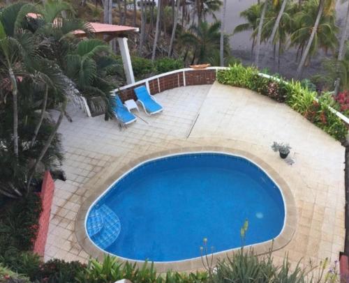 a large blue swimming pool with two blue chairs at Shalpa surf villa in La Libertad