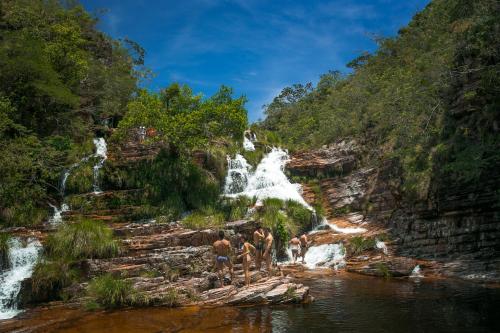 a group of people standing in the water near a waterfall at Cachoeiras Pé da Serra in São João Batista do Glória