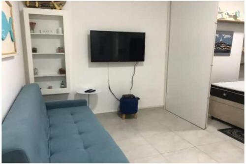 ein Wohnzimmer mit einem blauen Sofa und einem Flachbild-TV in der Unterkunft Apto com Wi-Fi bem perto da praia em Santos SP in Santos