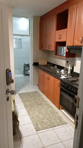 a kitchen with wooden cabinets and a tile floor at Walk To Beach 704 Umdloti Holiday Resort in Umdloti