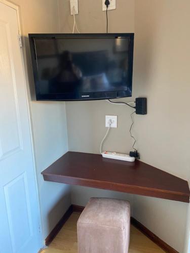 a desk with a tv on a wall with a wii at Nimza K Guesthouse in Kimberley
