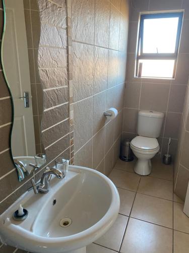 uma casa de banho com um lavatório e um WC em Nimza K Guesthouse em Kimberley