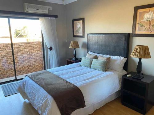 um quarto com uma cama grande, 2 candeeiros e uma janela em Nimza K Guesthouse em Kimberley