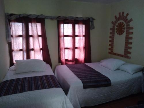 two beds in a room with two windows at Hotel Acatenango Inn in Antigua Guatemala