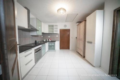 a kitchen with a white tile floor and white appliances at Apartmány na Šumavě in Stachy