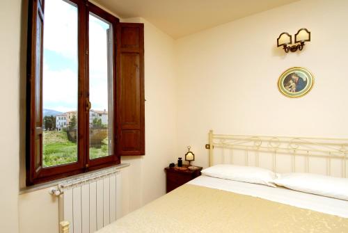 a white bedroom with a bed and a window at Antica Dimora delle Acque in Cannara