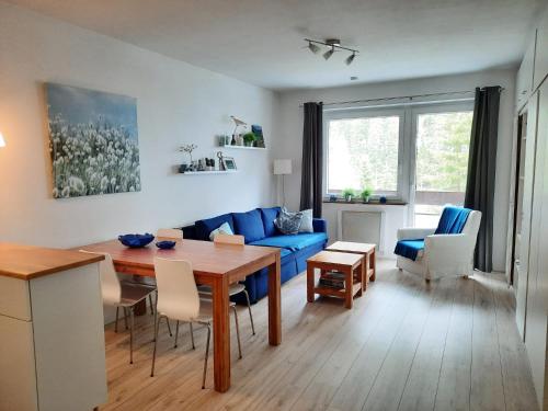 a living room with a blue couch and a table at Kinder- und Familienhotel Nockalm in Innerkrems