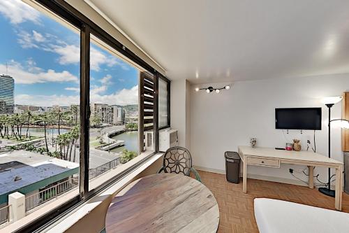 een woonkamer met een tafel en een groot raam bij Hawaiian Monarch 801 condo in Honolulu