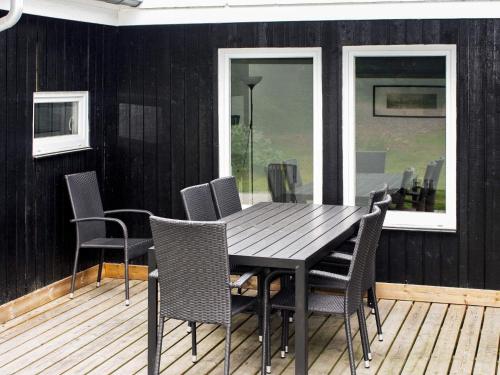 a black dining room table and chairs on a deck at 8 person holiday home in Hals in Hals