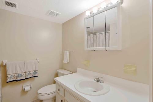 a white bathroom with a sink and a toilet at Inland condo with pool and steps to beach/food/shops in Marco Island