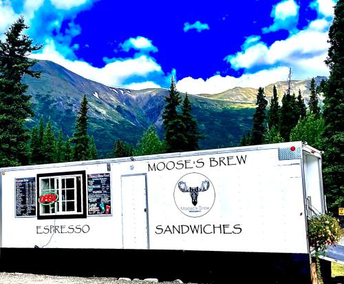 a trailer with a sign in front of a mountain at Carlo Creek Cabins in McKinley Park