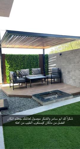 acovered patio with two benches and a table and grass at Golden White Hotel in Taif